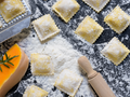Square butternut squash ravioli with crimped edges, dusted with flour on dough