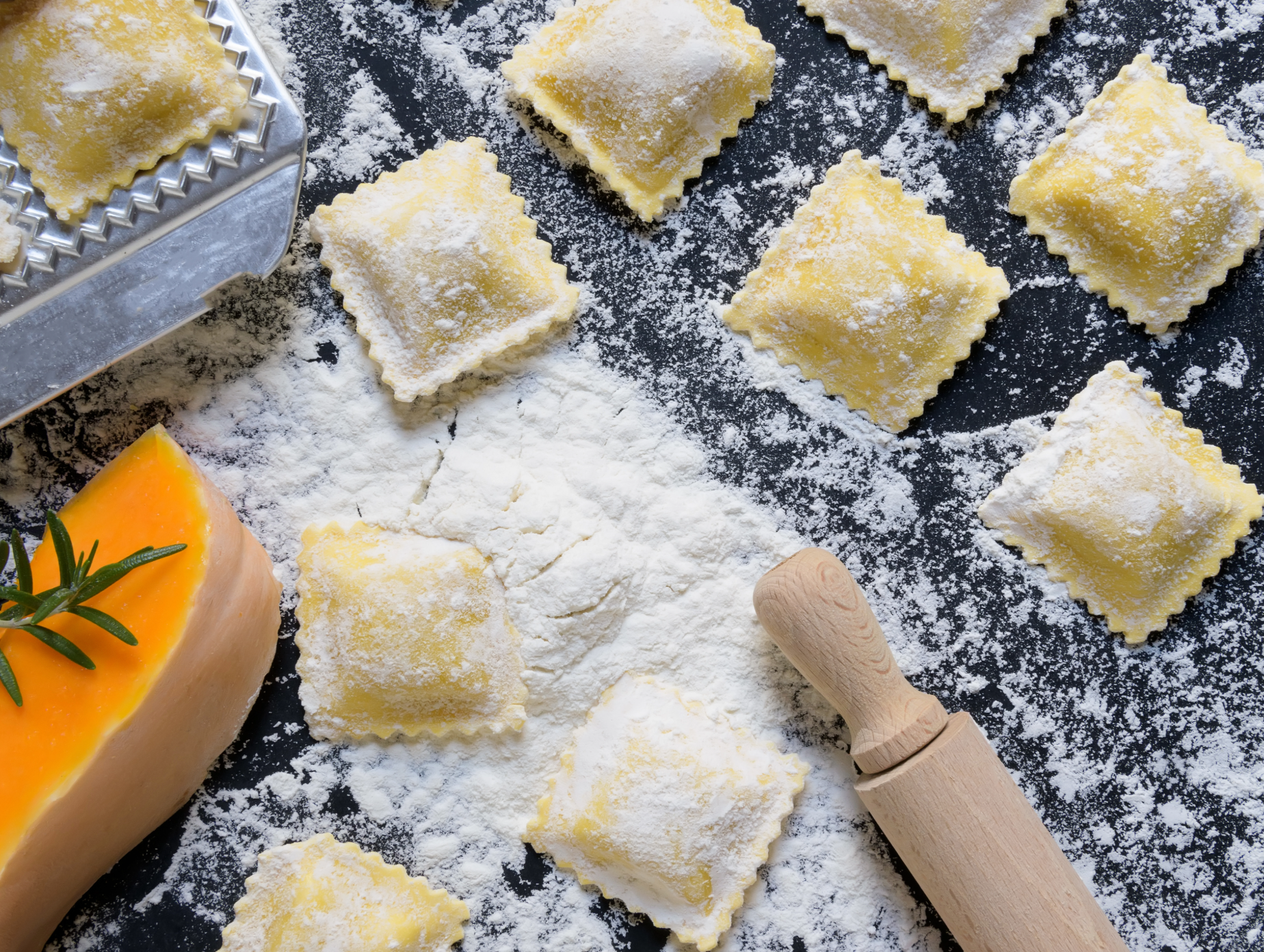 Square butternut squash ravioli with crimped edges, dusted with flour on dough