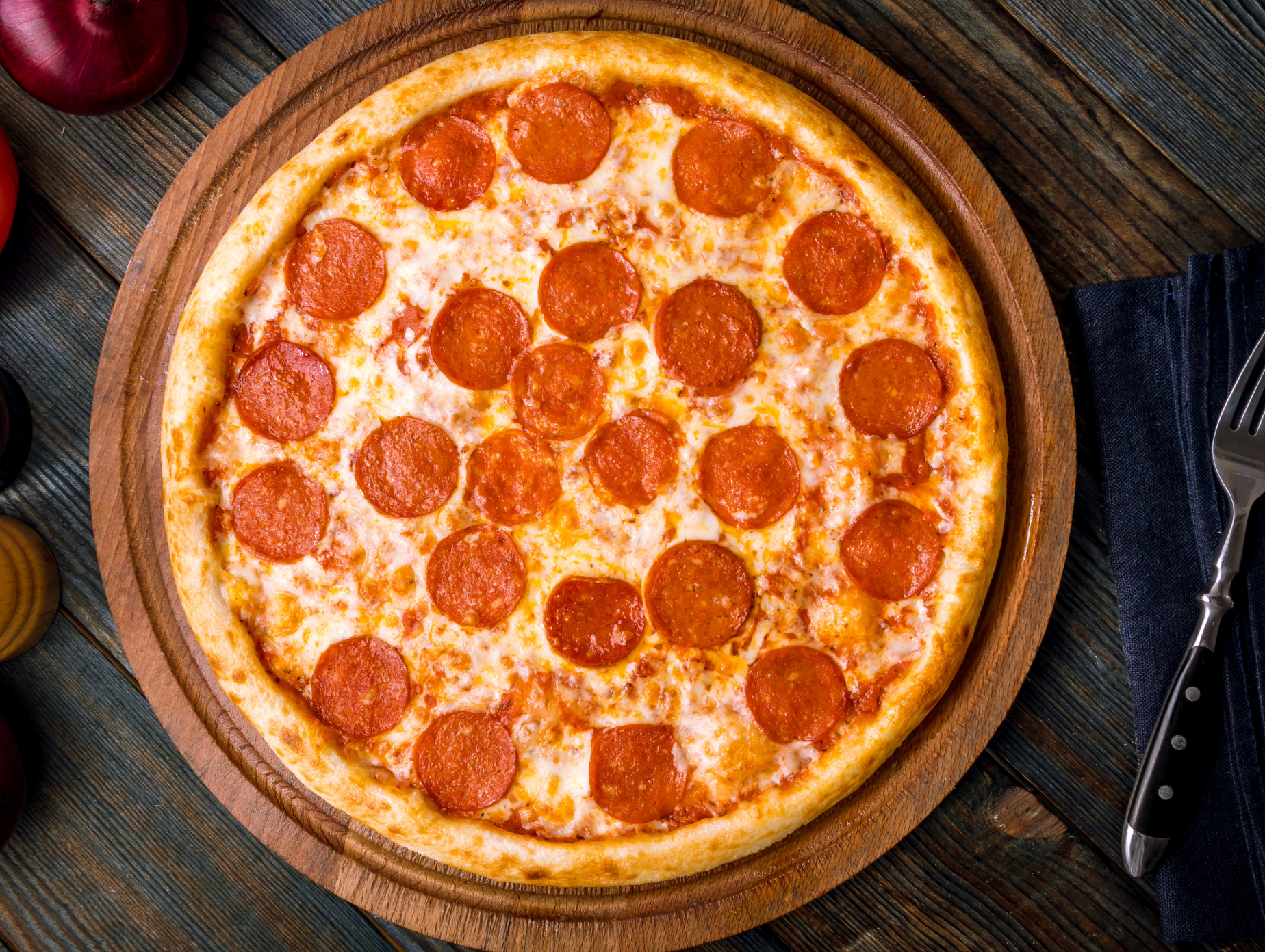 Pepperoni pizza with melted cheese and sliced pepperoni on a wooden board