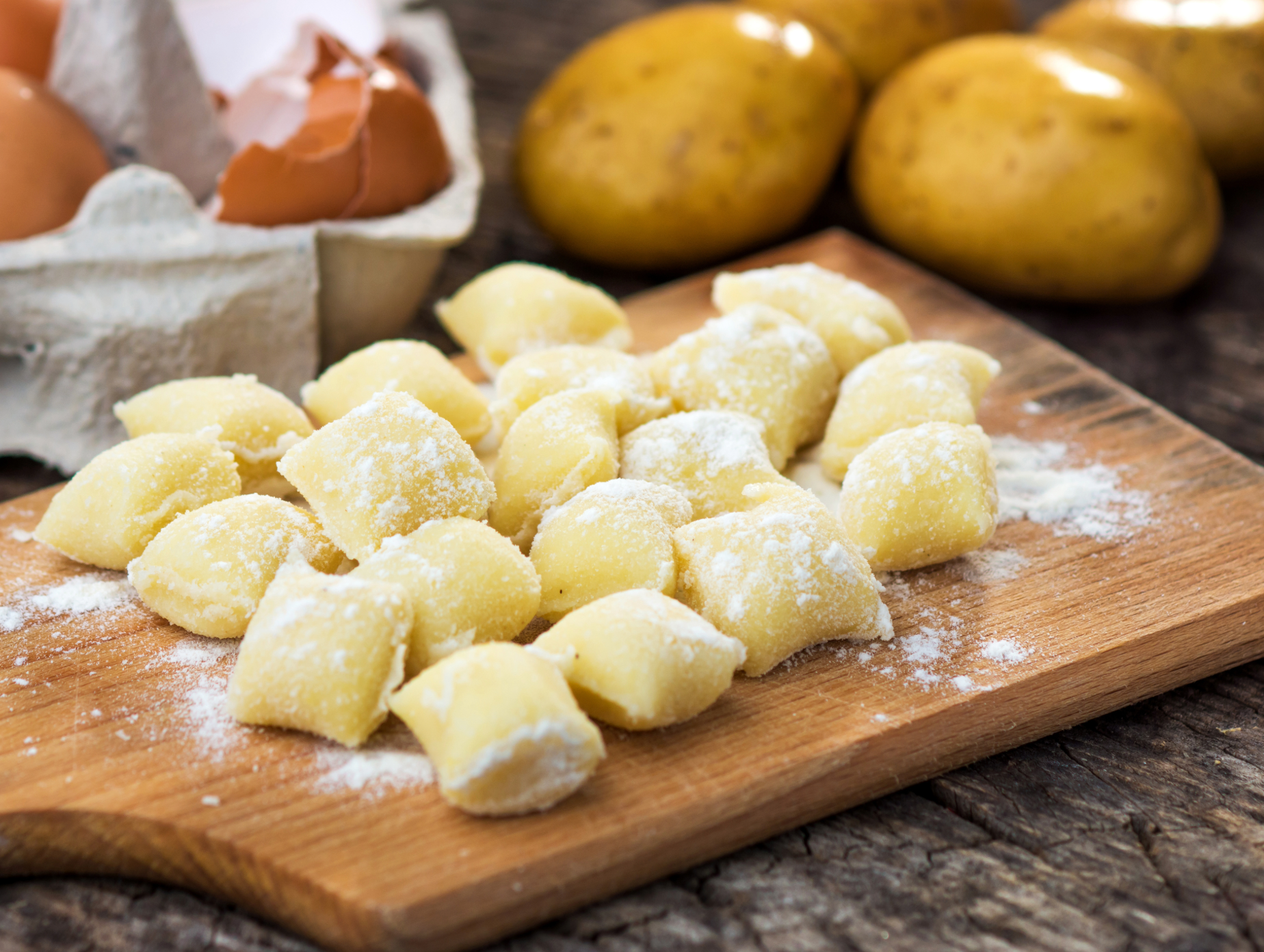 Potato gnocchi dumplings dusted with flour on a wooden board