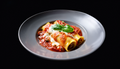 Chicken spinach cannelloni with red sauce, melted cheese, and basil garnish